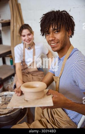 Happy young adults creating pottery in studio during daytime Stock Photo