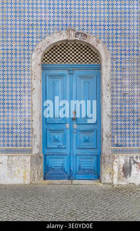 Blue wooden door with arched azulejo tiled facade, historic entrance, Lisbon, Portugal Stock Photo
