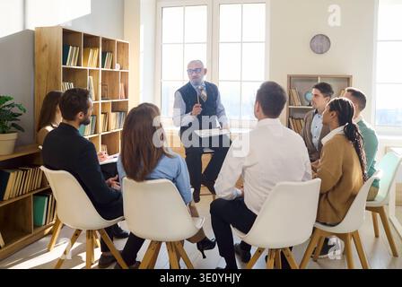 Experienced mentor guiding team in a circle for collaborative learning session Stock Photo