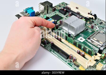 Hand installing RAM module into a computer motherboard slot for upgrade or repair Stock Photo