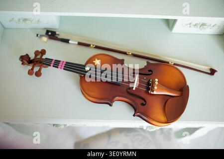 Close up of musical instrument with decorative stars on body lying on pastel furniture. Ideal for music education, classical art, hobbies and creative Stock Photo