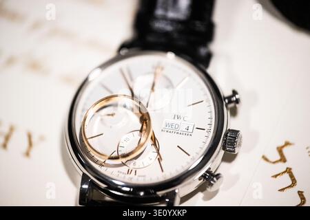 Luxury Watch with Wedding Rings on Elegant Invitation Detail. Close-up of a luxury wristwatch with gold wedding bands resting on its face Stock Photo
