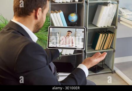 Businessman holding tablet with online video call during remote office meeting Stock Photo