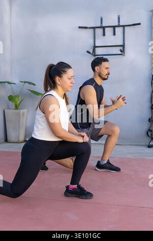 Two fitness instructors are performing lunges during an outdoor workout session, demonstrating proper form and technique for effective lower body stre Stock Photo