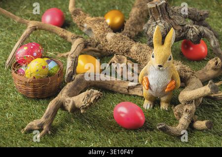 Bunny figure and Easter eggs between roots in the grass Stock Photo