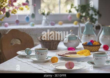 Decorated table with colorful easter eggs, pastries and cold platter Stock Photo