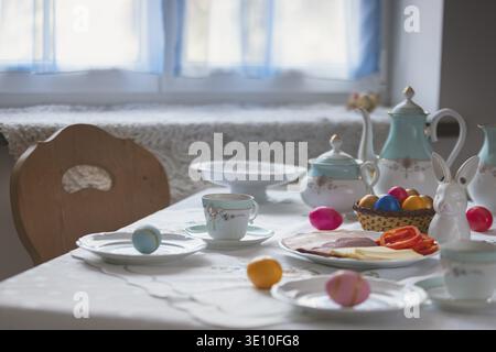 Decorated table with coffee pot, crockery, painted eggs and a porcelain bunny Stock Photo
