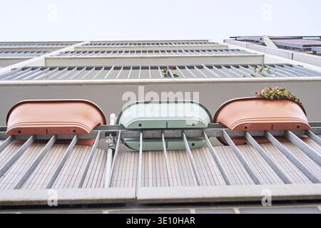 Plastic flower pots hang on the balcony of a rented apartment in a prefabricated building in Magdeburg, Saxony-Anhalt, Germany, view from below of bal Stock Photo