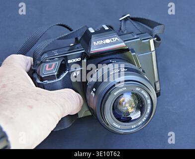 Hand holding a vintage Minolta 5000 film SLR camera with an AF zoom lens Stock Photo