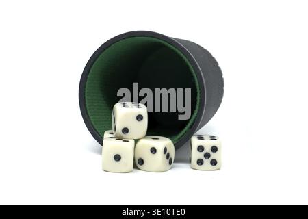 Four dice spilled from a green and black cup, isolated on a white background, representing games or chance activities. Perfect for themes of strategy Stock Photo