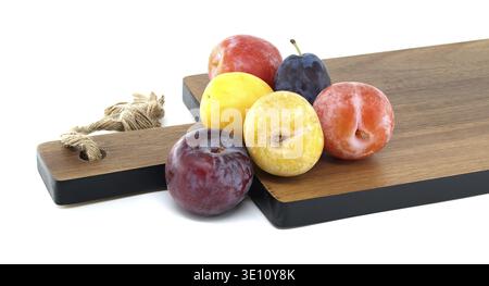 Fresh, colorful plums on a wooden cutting board showcasing vibrant fruit variety and healthy eating concept Stock Photo