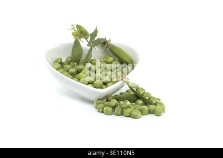 Fresh green peas in a heart-shaped bowl isolated on white background, with pea pods next to the bowl, perfect for concepts related to freshness, nutri Stock Photo