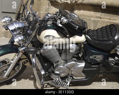 Gleaming Honda Shadow motorbike with an eagle sticker parked near a stone wall, showcasing its chrome details and powerful engine Stock Photo
