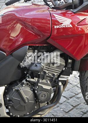 Red Honda motorcycle with engine details parked on a cobblestone street Stock Photo