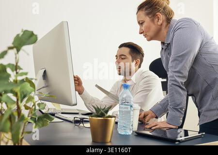 Business colleagues discussing financial data working together in office. People entrepreneurs working with charts and tables on computer. Two people Stock Photo