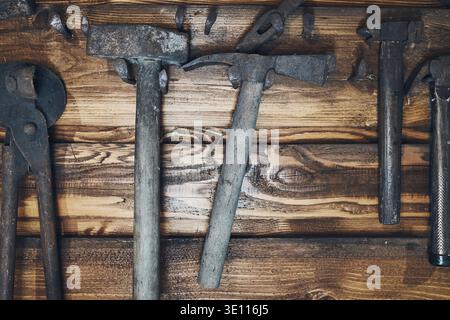 Old rusty blacksmith tools hung on wooden wall Stock Photo