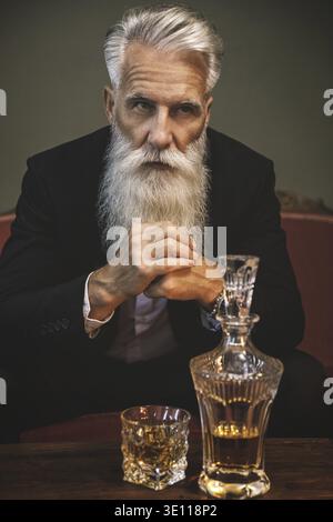 Stylish and handsome bearded senior man drinking whiskey Stock Photo