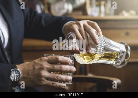 Man pouring expensive whiskey into the crystal drinking glass Stock Photo
