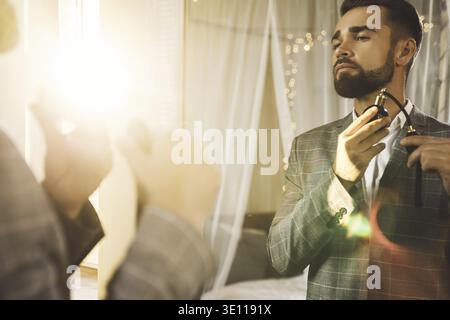 Young and handsome bearded man is using atomizer nozzle with perfume Stock Photo