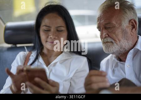 Portrait of mature multi-ethnic couple using mobile phone together inside the car Stock Photo
