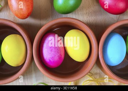 Brightly colored closeup easter eggs in clay bowls, holiday background Stock Photo