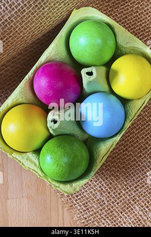 Brightly colored bow decorated easter eggs in egg carton holder, holiday background Stock Photo