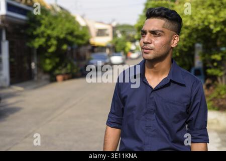 Portrait of young Indian businessman thinking in the streets outdoors Stock Photo