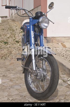 Classic blue Confersil motorcycle parked on a cobblestone street, showcasing its vintage design and chrome details Stock Photo