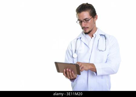 Studio shot of young handsome man doctor using digital tablet isolated against white background Stock Photo