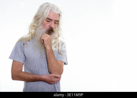 Studio shot of sad senior bearded man thinking while looking down Stock Photo