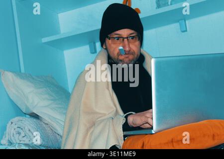 Man with flu feeling discomfort while sitting at home. Worried and ill human. Man with a flu feeling so bad but he must work. Stock Photo