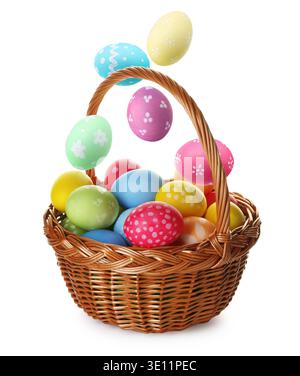 Bright Easter eggs falling into basket on white background Stock Photo