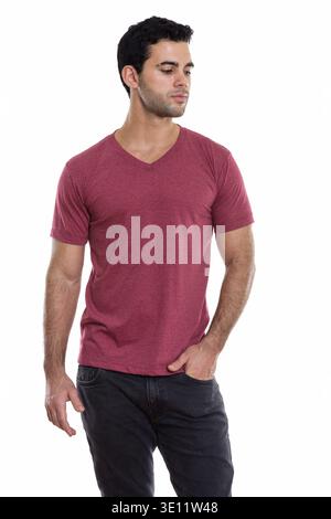Studio shot of young handsome Hispanic man posing while thinking and looking down Stock Photo