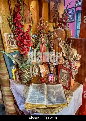 EL CARMEN, PERU - SEPTEMBER 26, 2025: A home shrine on a corner table in a house in El Carmen, Peru has an open bible and a figure of the Virgin Mary. Stock Photo
