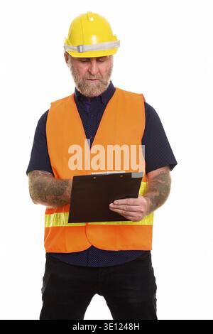 Mature bearded man construction worker with hand tattoos reading on clipboard Stock Photo