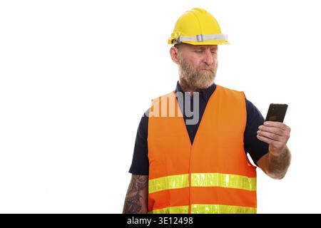 Mature bearded man construction worker with hand tattoos using mobile phone Stock Photo