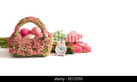 Easter flower basket with pink eggs, tulips and a rabbit clock on a white background. Happy Easter time. Banner. Copy space. Stock Photo