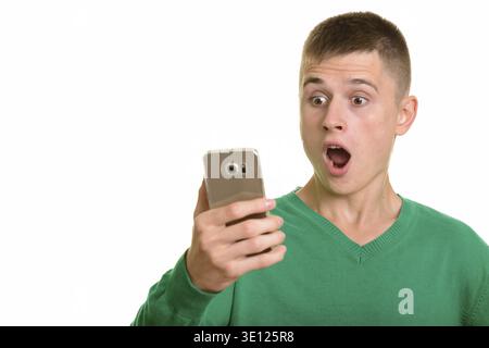 Young Caucasian man holding mobile phone looking surprised isolated against white background Stock Photo