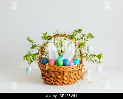 Easter composition with colorful painted eggs in a flower basket on a white background. Happy Easter time. Stock Photo
