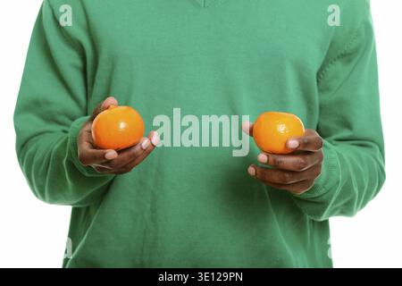 Young African man holding two oranges isolated against white background Stock Photo