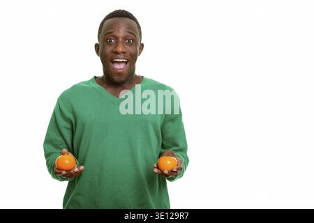 Young happy African man smiling while holding two oranges isolated against white background Stock Photo
