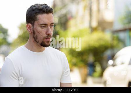 Young thoughtful man looking down outdoors Stock Photo