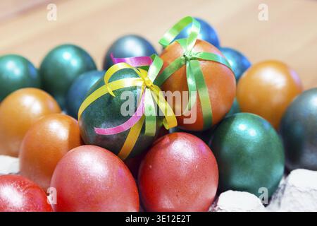 Brightly colored bow decorated easter eggs in egg carton holder, holiday background Stock Photo
