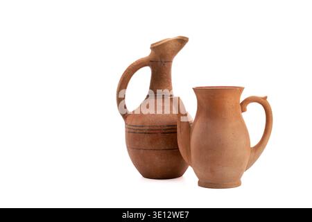 Two rustic terracotta pots stand side by side on white background. One has long neck and curved handle. Other is shorter, with rounded body and sturdy Stock Photo