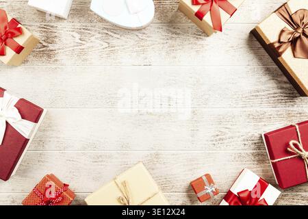 Gift boxes with colorful ribbons are lying on a white wooden table creating a frame with copy space Stock Photo