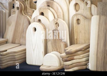 Close-up of handmade wooden cutting boards stacked in a variety of sizes and shapes, showcasing craftsmanship and natural wood grain Stock Photo