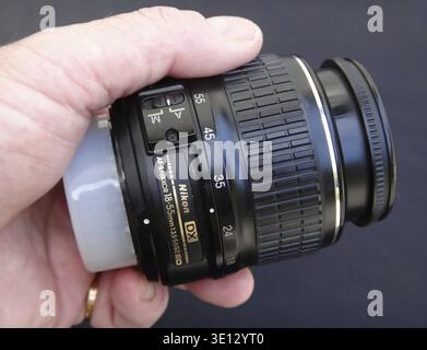 Photographer holding Nikon 18-55mm lens with lens cap Stock Photo