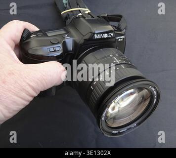 Hand holding a vintage Minolta Dynax 3xi 35mm film camera with a Sigma 28-200mm zoom lens Stock Photo