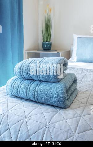 Turquoise towels folded on bed in guest room for hotel customer Stock Photo