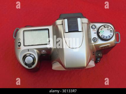 Top view of vintage analog film camera Nikon F65 lying on red background Stock Photo